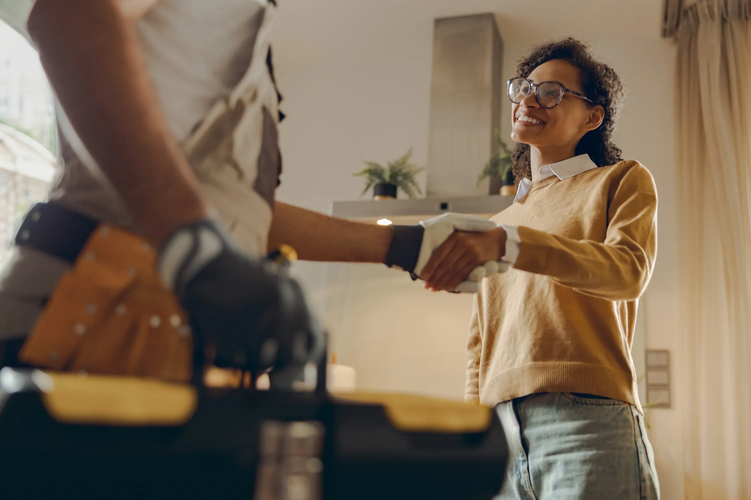 Poignée de main entre un artisan expert et une cliente satisfaite après devis