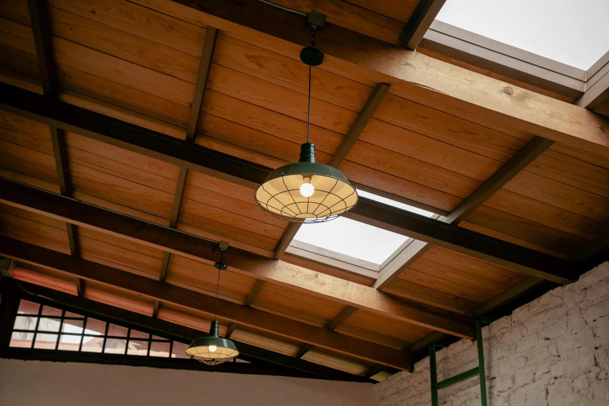 Plafond avec charpente en bois apparente et luminaires industriels après rénovation